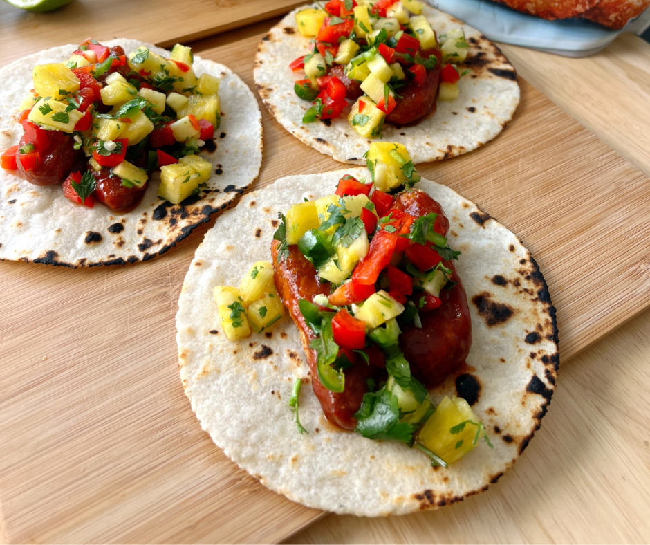 three BBQ Plant-Based Chicken Tacos with Pineapple Salsa on a cutting board