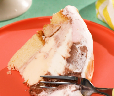 a fork cutting into a slice of baked alaska on an orange plate