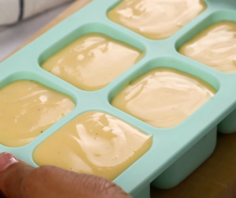 an ice tray filled with cheese sauce