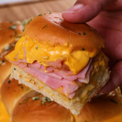 hand holding a ham and cheese slider