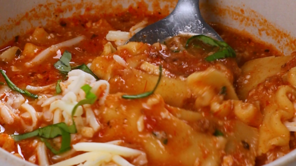 A small silver spoon mixing a bowl of lasagna soup