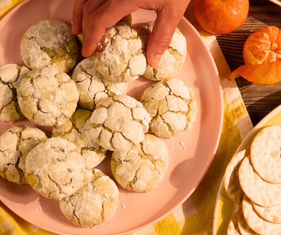 a hand grabbing a cookie from a plate of cookies