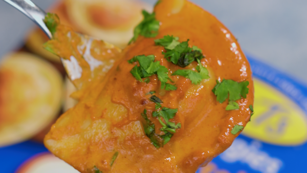 Close up shot of a sauce covered pierogi on a fork