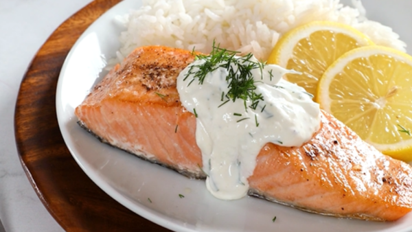 Cooked salmon filet, rice, and lemon slices on a white plate