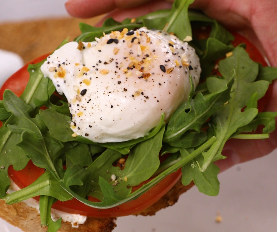 toast topped with tomato, arugula, and a poached egg